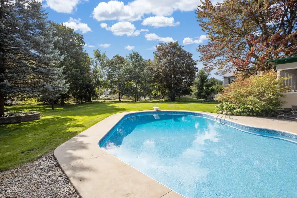 a large swimming pool in a backyard surrounded by trees